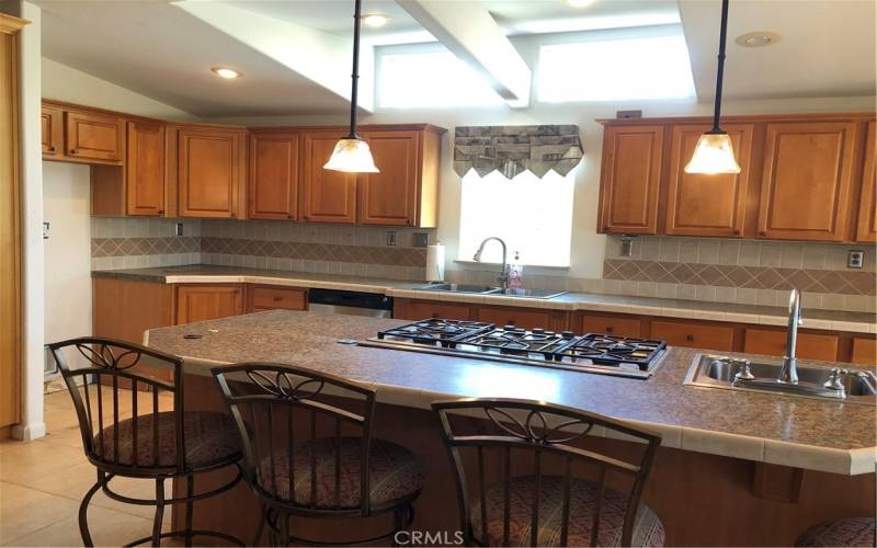 Large kitchen island has 5-burner propane cooktop and prep sink.