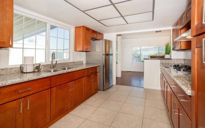 A spacious kitchen with a new stainless steal refrigerator, gas cooking and granite counter tops.