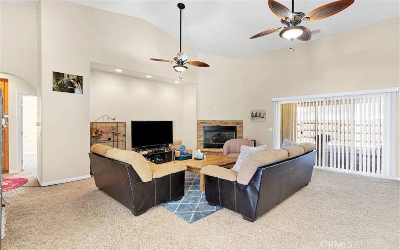 Large living room with corner fireplace. Dual lighted ceiling fans. Triple door lets in plenty of natural light from the covered patio area.