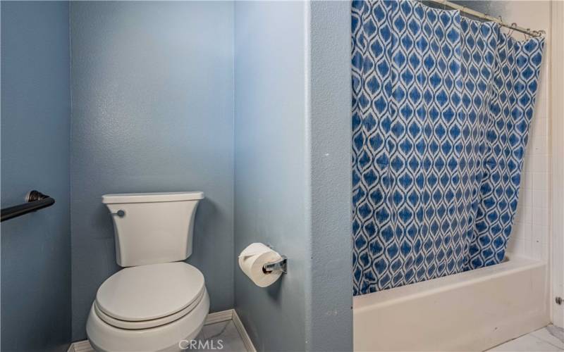 Secondary bathroom is a tub/shower combo, toilet and vanity sink with mirror and light.