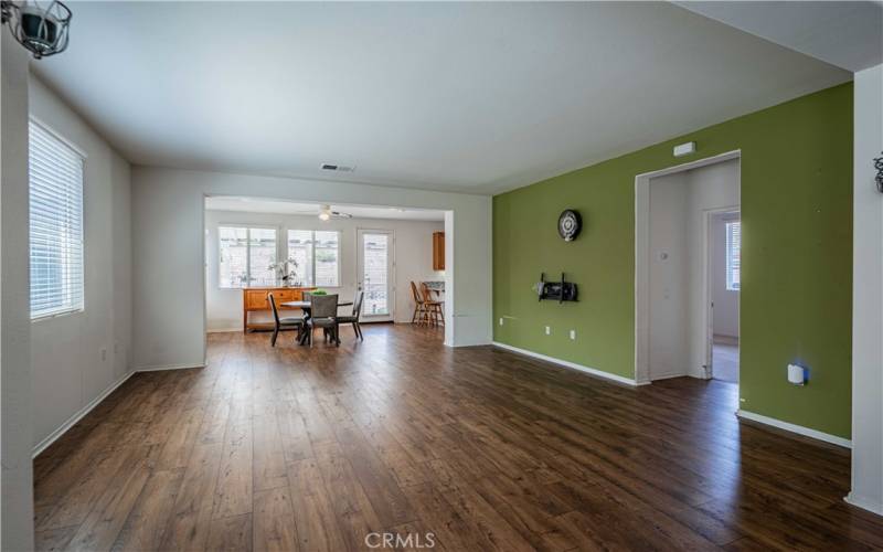 Front room opens to the family room then dining room at the far end. Kitchen is nicely tucked behind the green wall, far back right. Wood laminate flooring is waterproof.