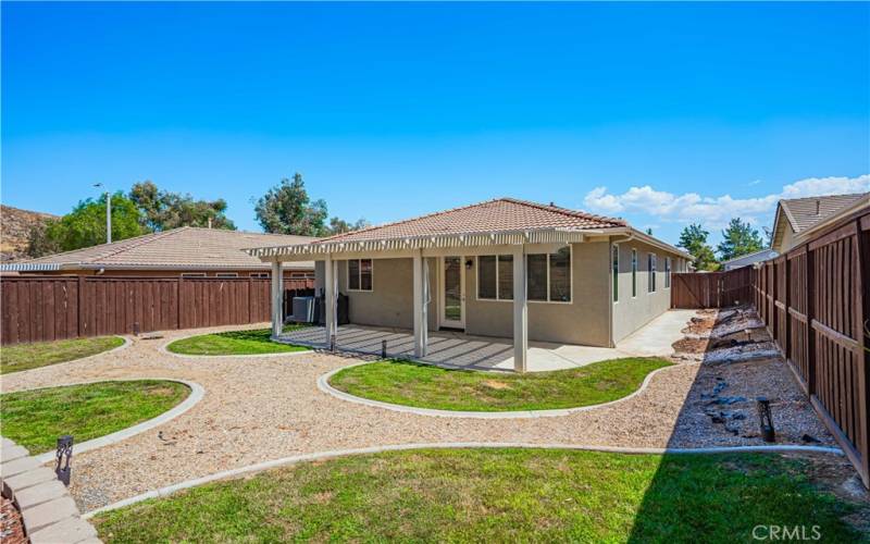 Back yard is darling with an alumawood patio that has concrete underneath, and pull down shades for privacy. 5 distinct grass areas trimmed in a rock path. Wood fence surrounds you.Concrete path  also on the side of the home.