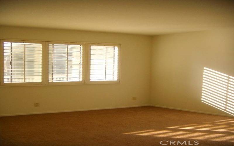 Secondary bedroom with carpet and shutters.