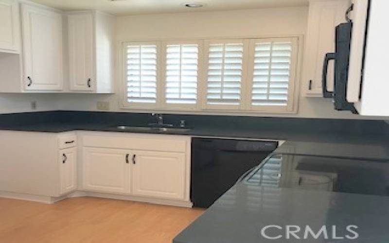 Remodeled kitchen with stone counters, plantation shutters and new cabinets. SS sink and electric stove with microwave above it.