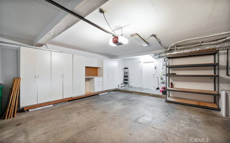 An abundance of storage in garage with cabinets on one wall and floor to ceiling shelving on other two walls.