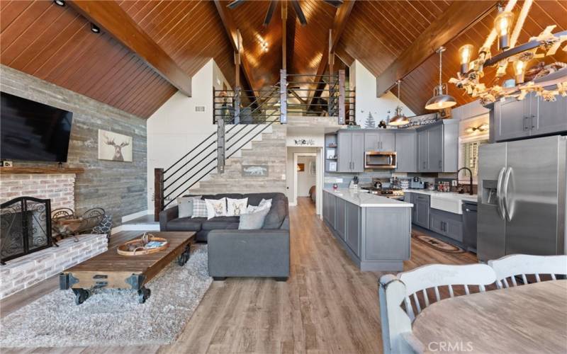 Living room, kitchen, and dining nook with vaulted ceilings and exposed beams