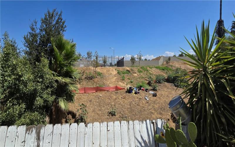 There's a retaining wall under the wood fence with a wash behind it and more land beyond that!