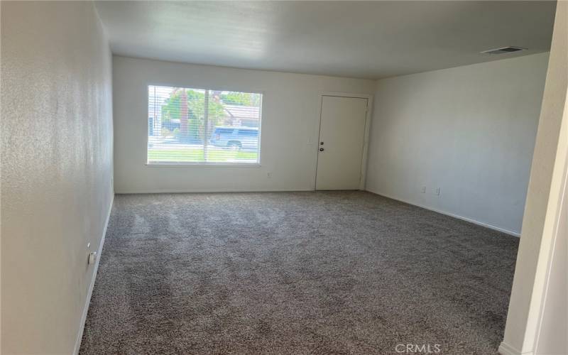 Spacious living room with smooth ceiling, fresh paint, new blinds and new carpet.