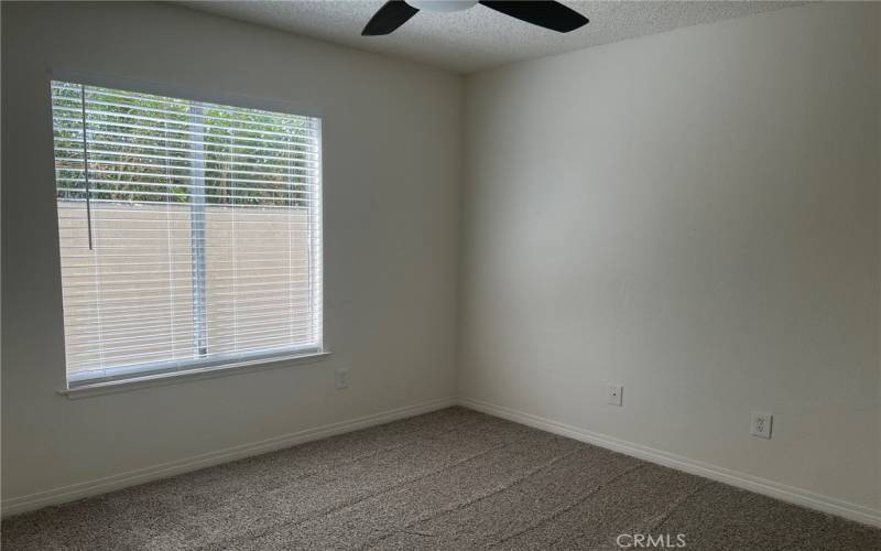 A smaller bedroom has a ceiling fan and faces the front porch.