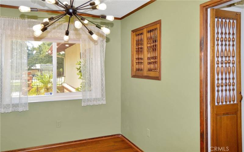 Formal dining room with fun lighting, pocket doors to the living room, custom wood doors and a pass-through to the kitchen, and more gorgeous wood flooring. This could make a great home office instead with courtyard views to enjoy.