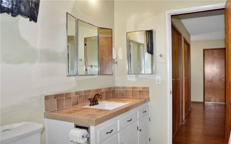 Now back to the main bedroom's en suite bath. It is accessible from the main suite and the laundry room and has a good-sized vanity, tri-fold mirror, and a tub/shower combo. It needs a paint touch up, so imagine what color you'll make it once it's yours!