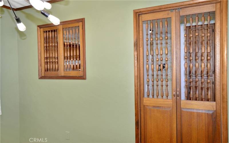 Formal dining room with fun lighting, pocket doors to the living room, custom wood doors and a pass-through to the kitchen, and more gorgeous wood flooring. This could make a great home office instead with courtyard views to enjoy.