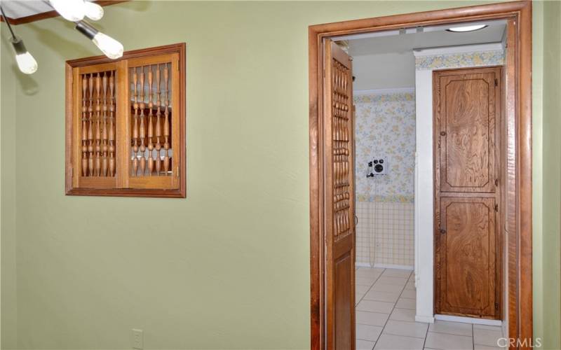 Formal dining room with fun lighting, pocket doors to the living room, custom wood doors and a pass-through to the kitchen, and more gorgeous wood flooring. This could make a great home office instead with courtyard views to enjoy.