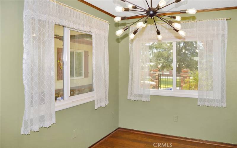 Formal dining room with fun lighting, pocket doors to the living room, custom wood doors and a pass-through to the kitchen, and more gorgeous wood flooring. This could make a great home office instead with courtyard views to enjoy.