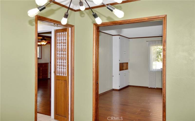 Formal dining room with fun lighting, pocket doors to the living room, custom wood doors and a pass-through to the kitchen, and more gorgeous wood flooring. This could make a great home office instead with courtyard views to enjoy.