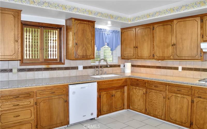 Expansive kitchen with abundant cabinet space, granite counter tops, tile flooring, and refrigerator included