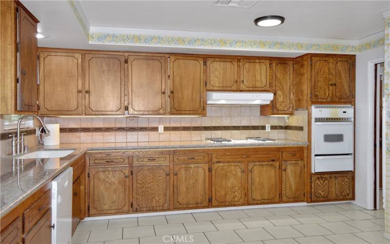 Expansive kitchen with abundant cabinet space, granite counter tops, tile flooring, and refrigerator included