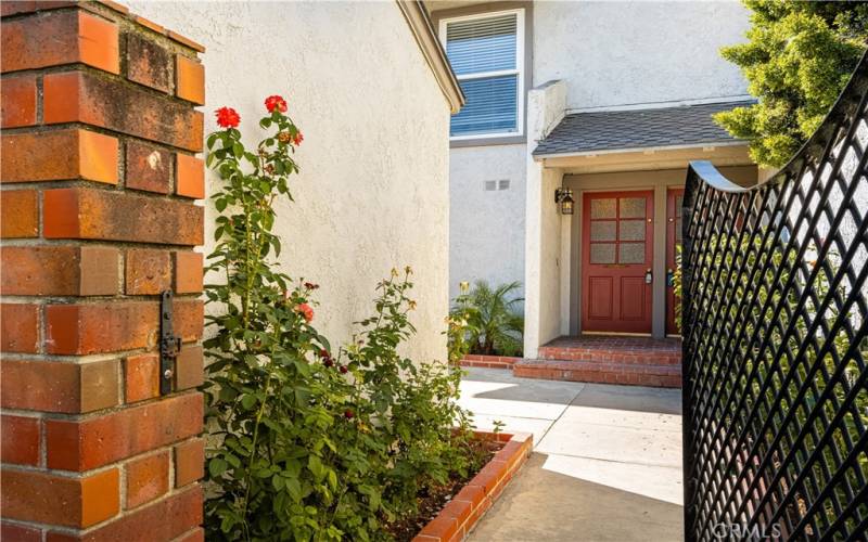 Inviting front entrance with brick accents and lush greenery