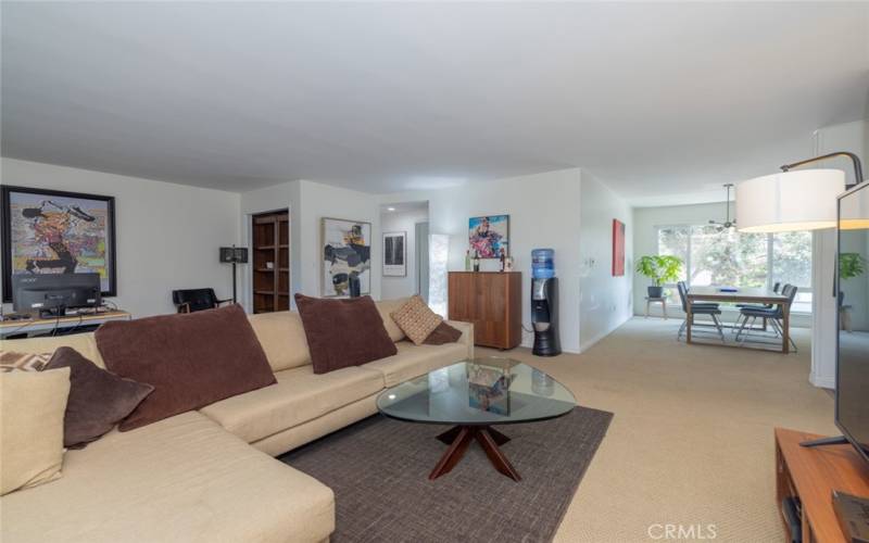 Living room already furnished with sectional sofa, glass top coffee table, TV stand, looking toward to separate formal dining room.