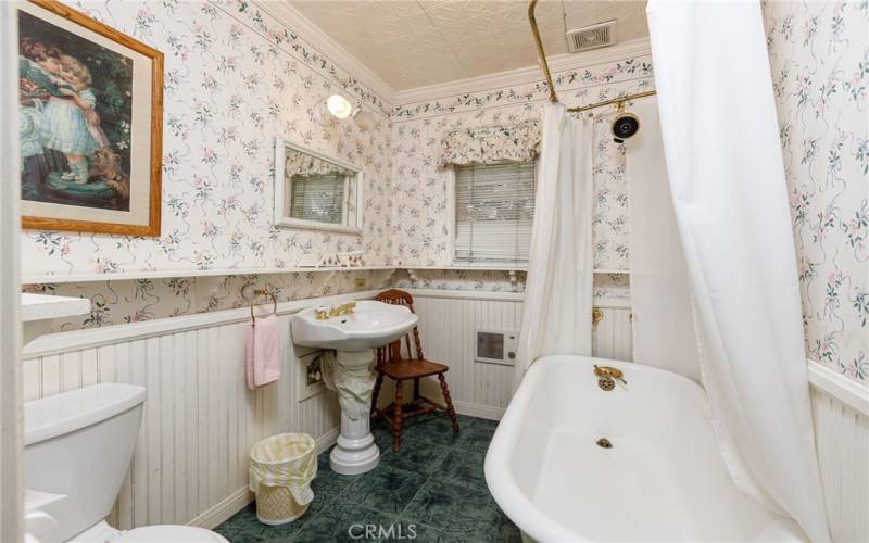 Main level full bath with clawfoot tub and wainscotted walls.