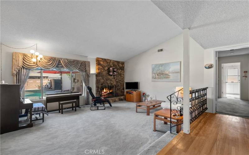 Spacious living room with vaulted ceilings, a fireplace and view to the backyard pool.