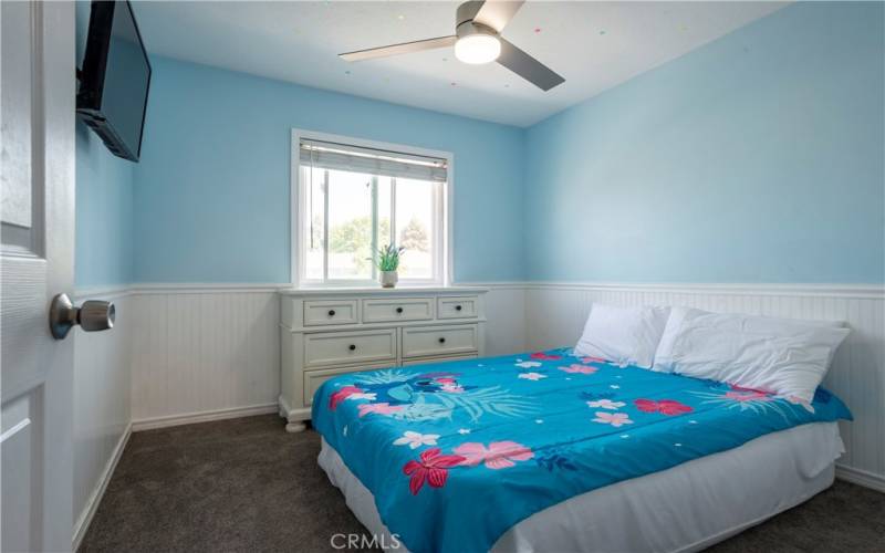 Bedroom 3 with fan fixture and decorative wainscoting