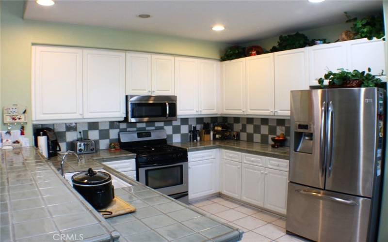 Practical Kitchen Footprint with Stainless Appliances and Custom Counters and Backsplash.