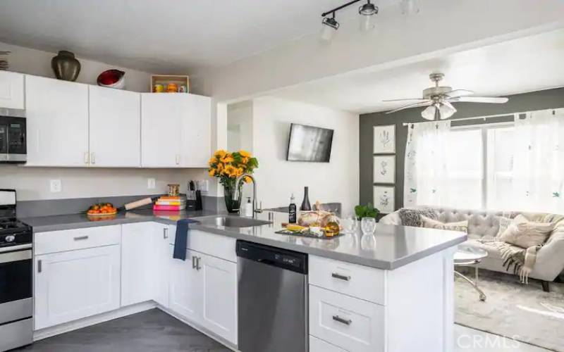 View of kitchen with lots of cabinets, eating bar and family room area.