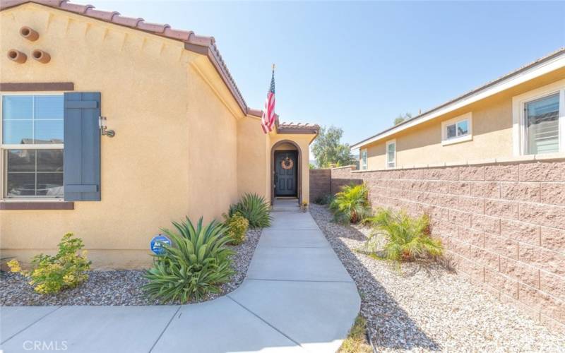 The welcoming entry features a beautifully maintained pathway leading to a charming front door that is surrounded by vibrant landscaping.