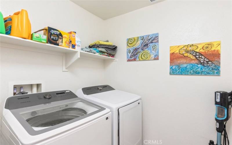 
This convenient in-house laundry room features modern appliances, built-in shelving, and ample space for storage and organization.