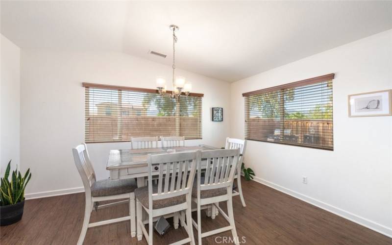 
This bright dining area features large windows, wood flooring, and a modern chandelier, creating a welcoming space for meals and gatherings.