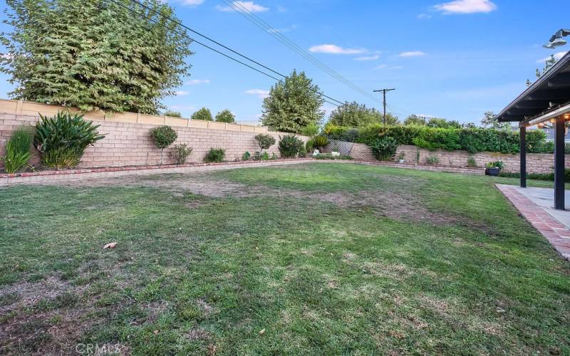 The beautiful private backyard will be a favorite entertainment destination with its green lawn, colorful raised flowerbeds, mature shade trees, expansive covered patio with lighted ceiling fans, and a built-in brick BBQ island with sink and tile countertops.