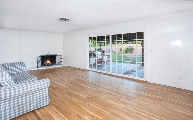 The family room is bathed in natural light and is enhanced by a floor-to-ceiling brick fireplace with mantle, newly refinished original oak hardwood floors and a large sliding French door that lead to the backyard.