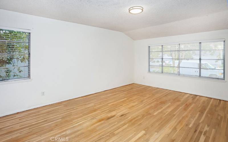 The generously sized primary bedroom is drenched in natural light from glistening windows, ample closet space and newly refinished original oak hardwood floors.