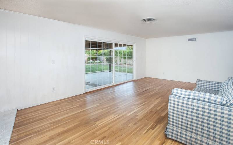 The family room is bathed in natural light and is enhanced by a floor-to-ceiling brick fireplace with mantle, newly refinished original oak hardwood floors and a large sliding French door that lead to the backyard.