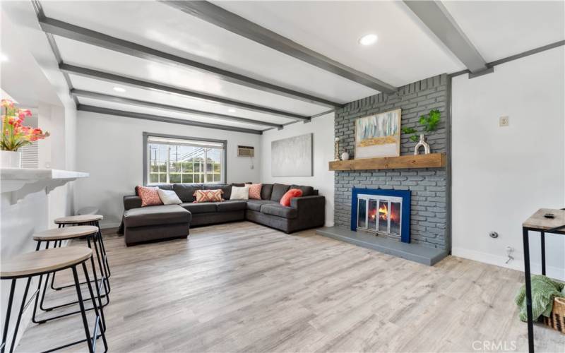 Roomy family room with brick fireplace and recessed lighting. Window in distance faces the front yard.