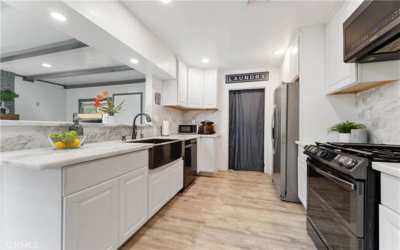 Updated kitchen with marble counters/backsplash, recessed lighting. Indoor laundry in the distance with exterior door to the back patio and another exterior door to the back from the family room.