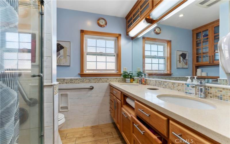 Full bathroom with quartz counters and tiled flooring and half wall.