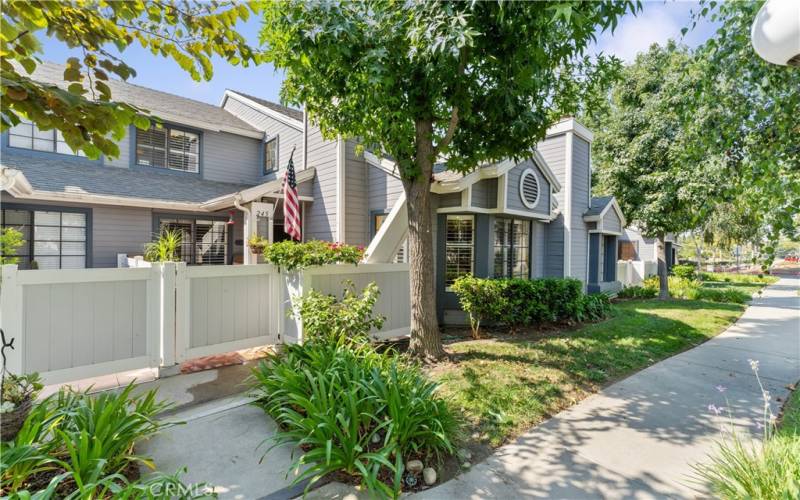 The gate nearest the American flag is to the patio of the unit. The bay windows near the bushes is the living room of the unit.