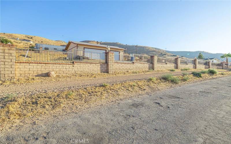 Partially fenced property surrounds garage facilities with two access areas including one rolling gate.