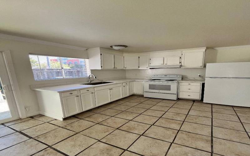 Kitchen with new countertop and sink. Sliding door and window to enclosed patio.