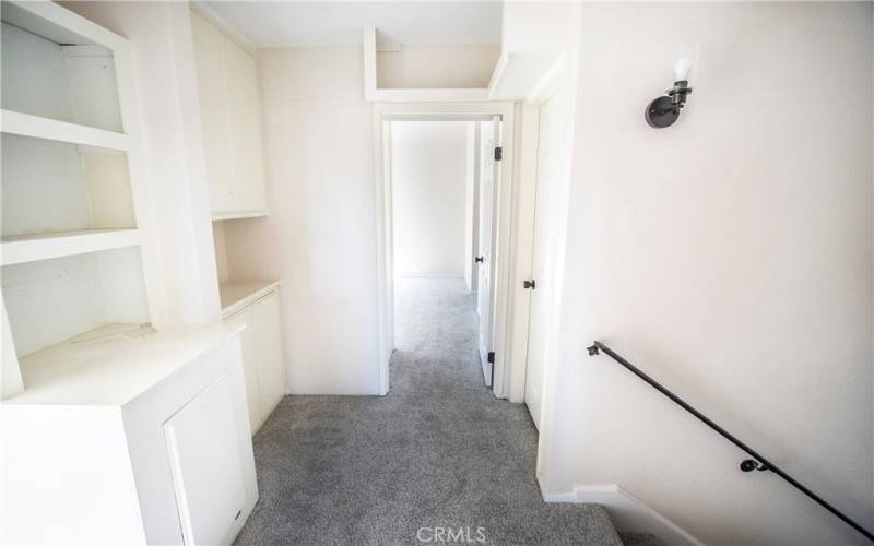 Upstairs hallway with builtins and laundry chute to garage