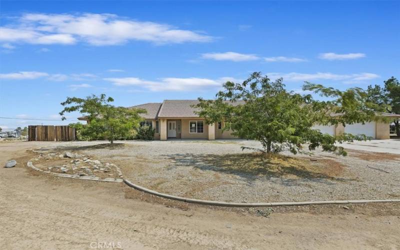 There is a long, wide driveway and some hardscape curbing in front.