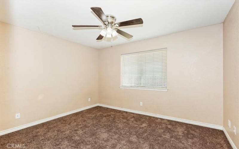 Secondary bedroom three faces the backyard. Ceiling fans throughout for your comfort.