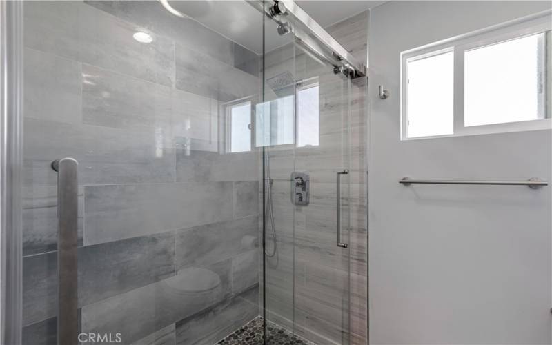 Primary bathroom with Newer shower installed and pebble tile flooring