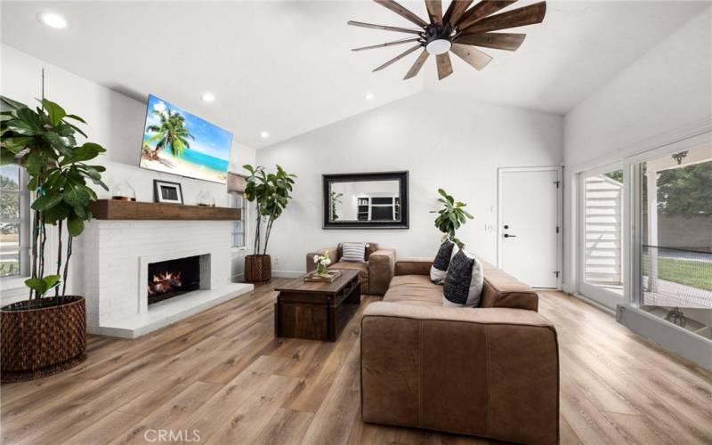 Oversized family room with large ceiling fan and fireplace.