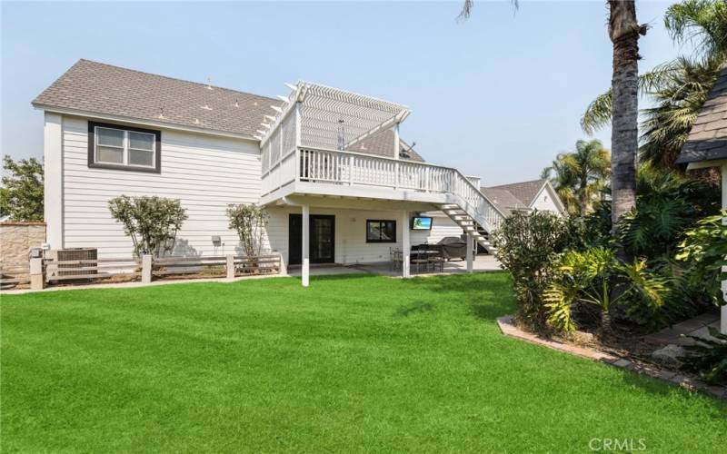 Flat backyard with view of the covered patio/balcony area.