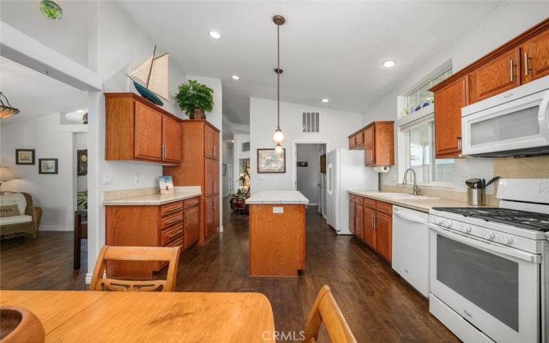 Spacious modern kitchen with sleek countertops and simulated wood laminate flooring that work well together complimented with natural wood cabinets.