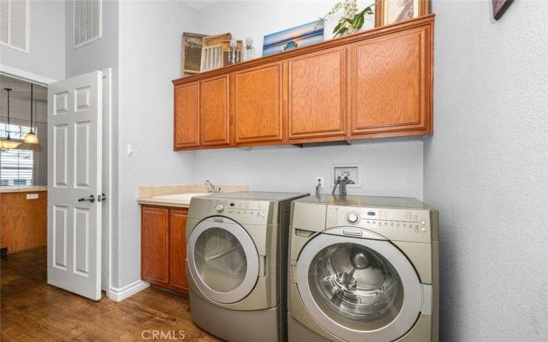 VERY SPACIOUS inside laundry room that features a sink and lots of overhead storage including a large broom closet.