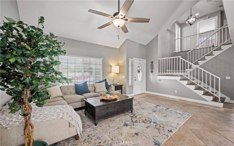 Living Room features tile floor, ceiling fan, blinds